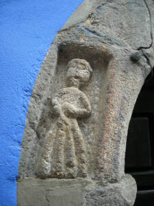 Detalle de la muñeca labrada en piedra en el arco de la puerta. También se muestra parte de su característica fachada azul