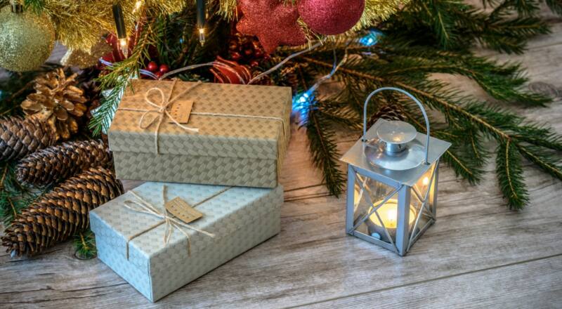 Dos cajas de regalo junto al pie de un árbol de Navidad