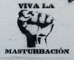 Grafitti en negro de un puño cerrado y la frase: Viva la masturbación.