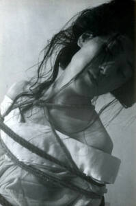Foto en blanco y negro de una mujer con ataduras de cuerdas alrededor del cuello y torso.