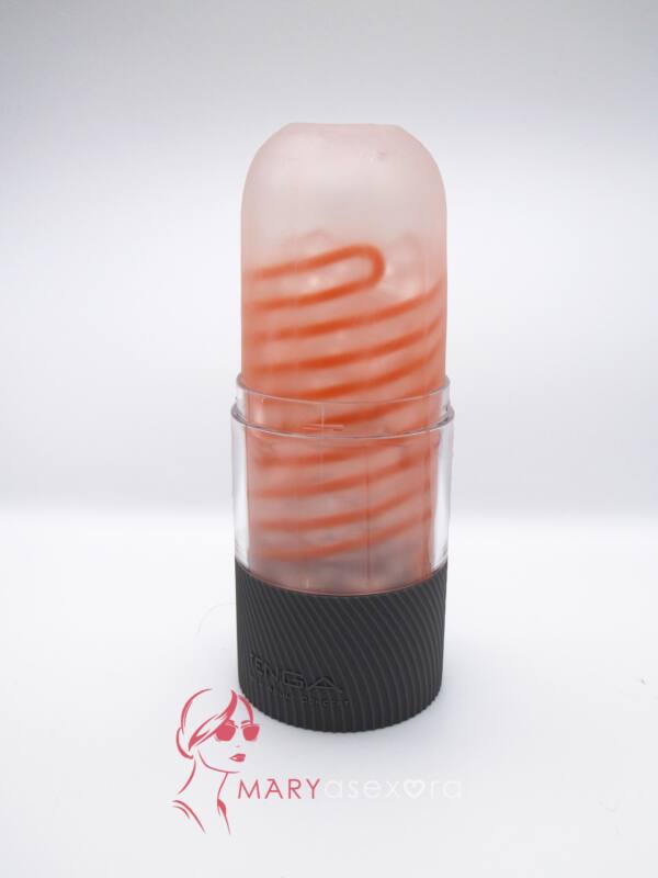 TENGA Spinner Hexa masturbador transparente con espirales rojas apoyado en la base del embalaje