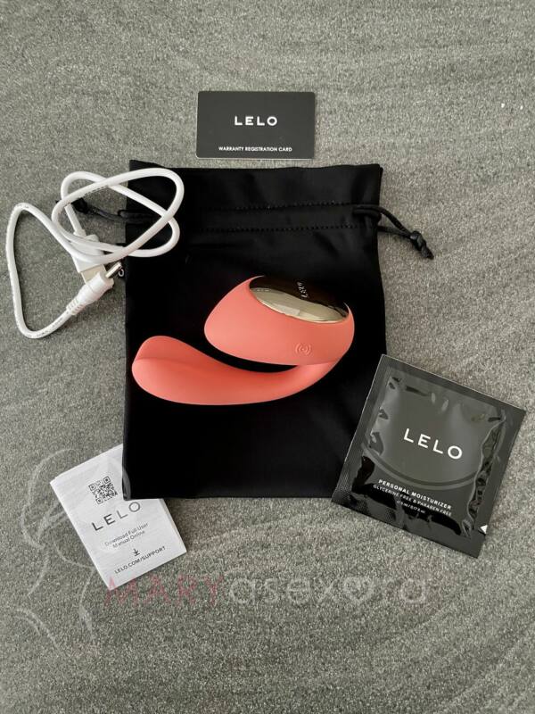 Contenido vibrador LELO IDA Wave: estimulador curvado en color coral red, cable cargador USB, monodosis lubricante, funda satén negra, tarjeta garantía, manual de instrucciones.