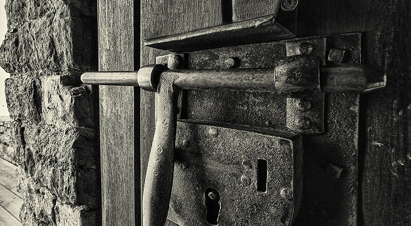Foto en blanco y negro de un cerrojo en una puerta de madera