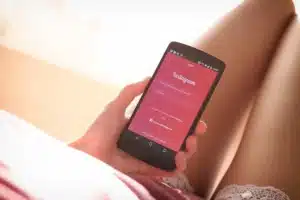 Mujer Sosteniendo Smartphone Negro con app de Instagram en pantalla